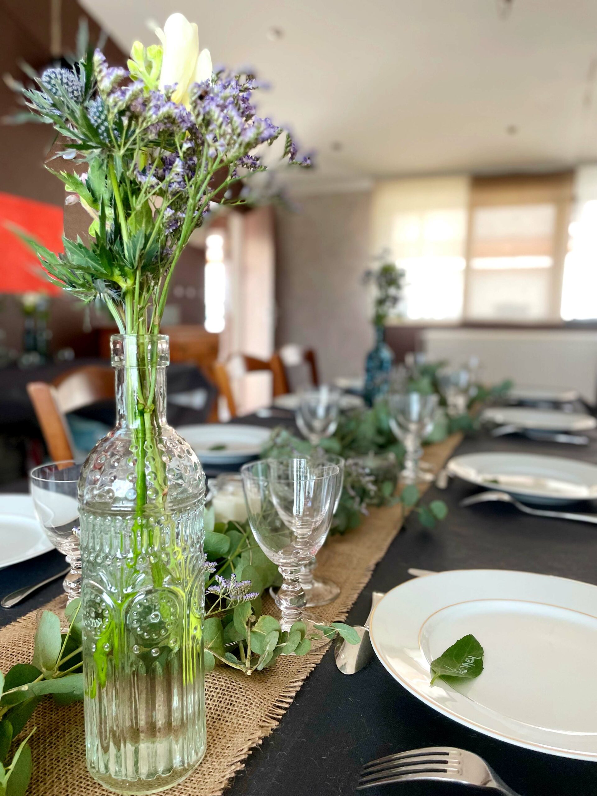 table décorées avec une bouteille contenant des fleurs violettes